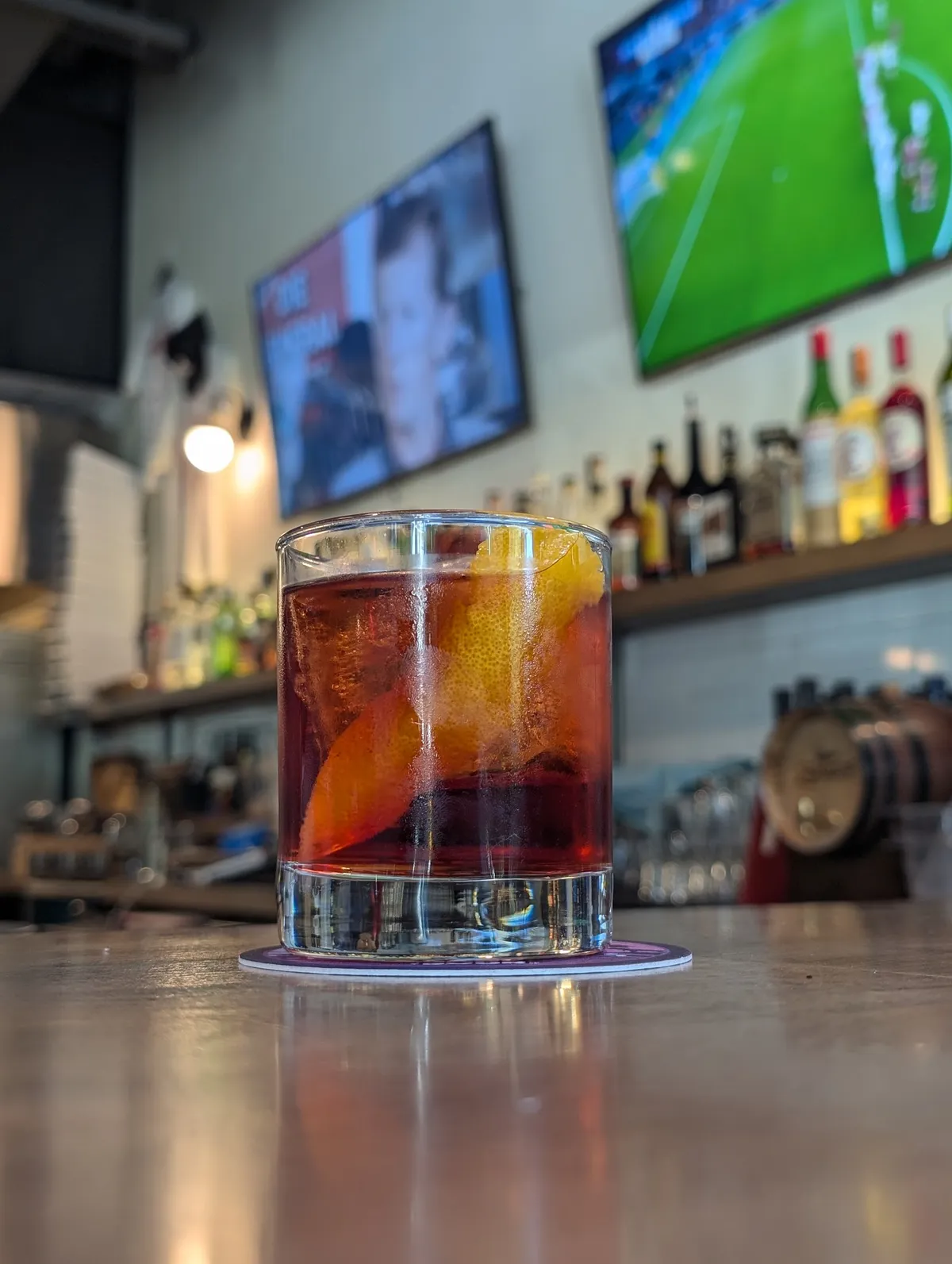 Red cocktail with citrus garnishes on a bar counter